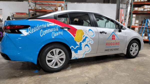 Car with a custom advertising wrap for a cleaning company inside a shop