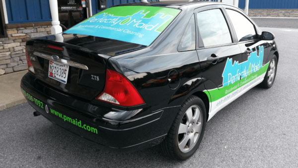 Black car with an advertising vehicle wrap for a cleaning company