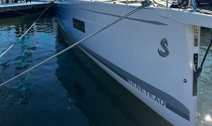 Bow view of a Beneteau sailboat featuring a sleek custom wrap by AP Wraps, with branding details and seahorse emblem clearly visible above the waterline
