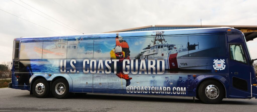us-coast-guard-bus-wrap-graphics-high-quality-materials U.S. Coast Guard bus with custom wrap graphics showcasing high-quality bus wrap materials and full-color design.