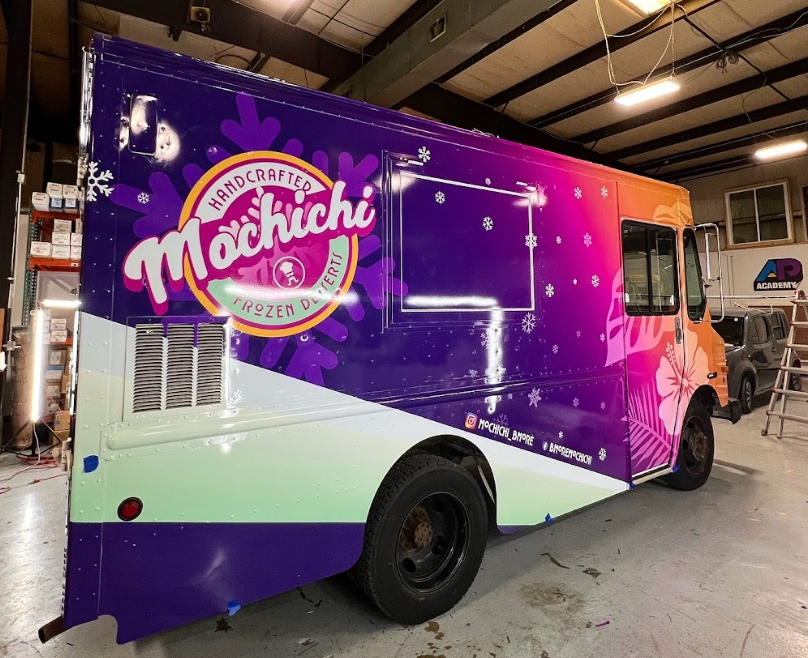 Vibrantly wrapped Mochichi food truck parked inside a workshop.