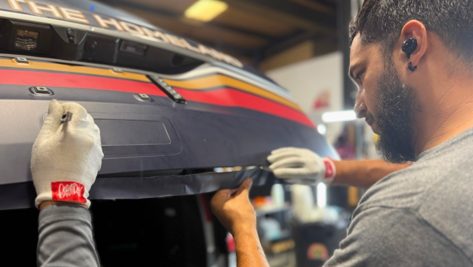 A skilled professional performing vehicle wrap maintenance on a company vehicle.