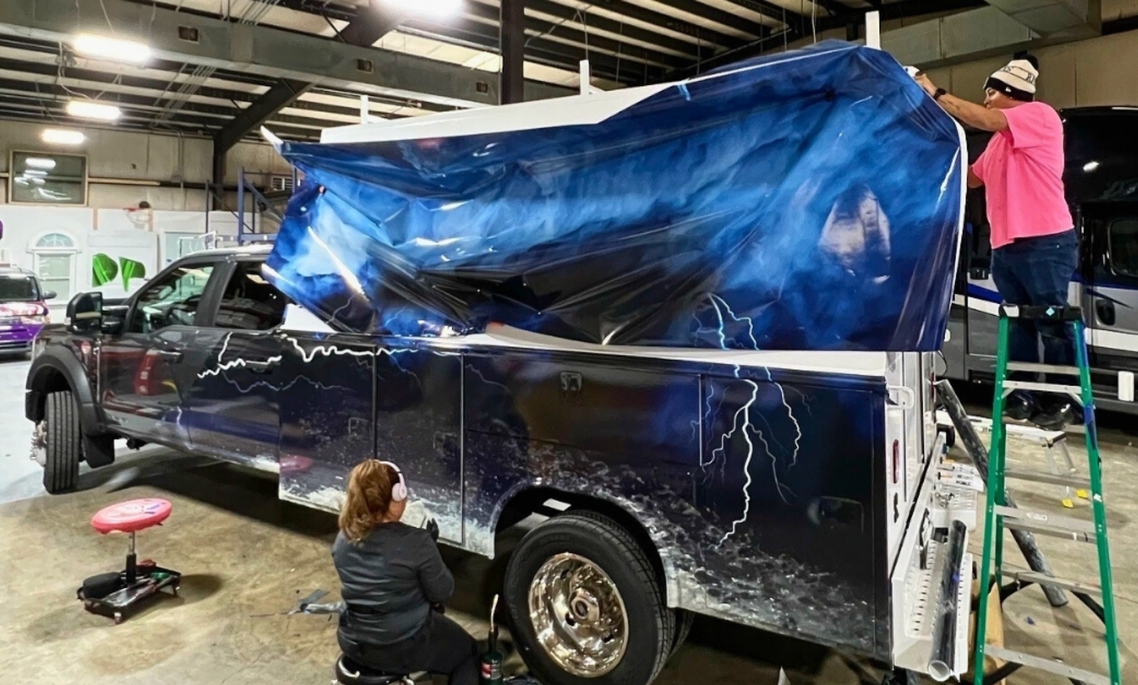 Skilled professionals performing vehicle wrap maintenance on a company vehicle.