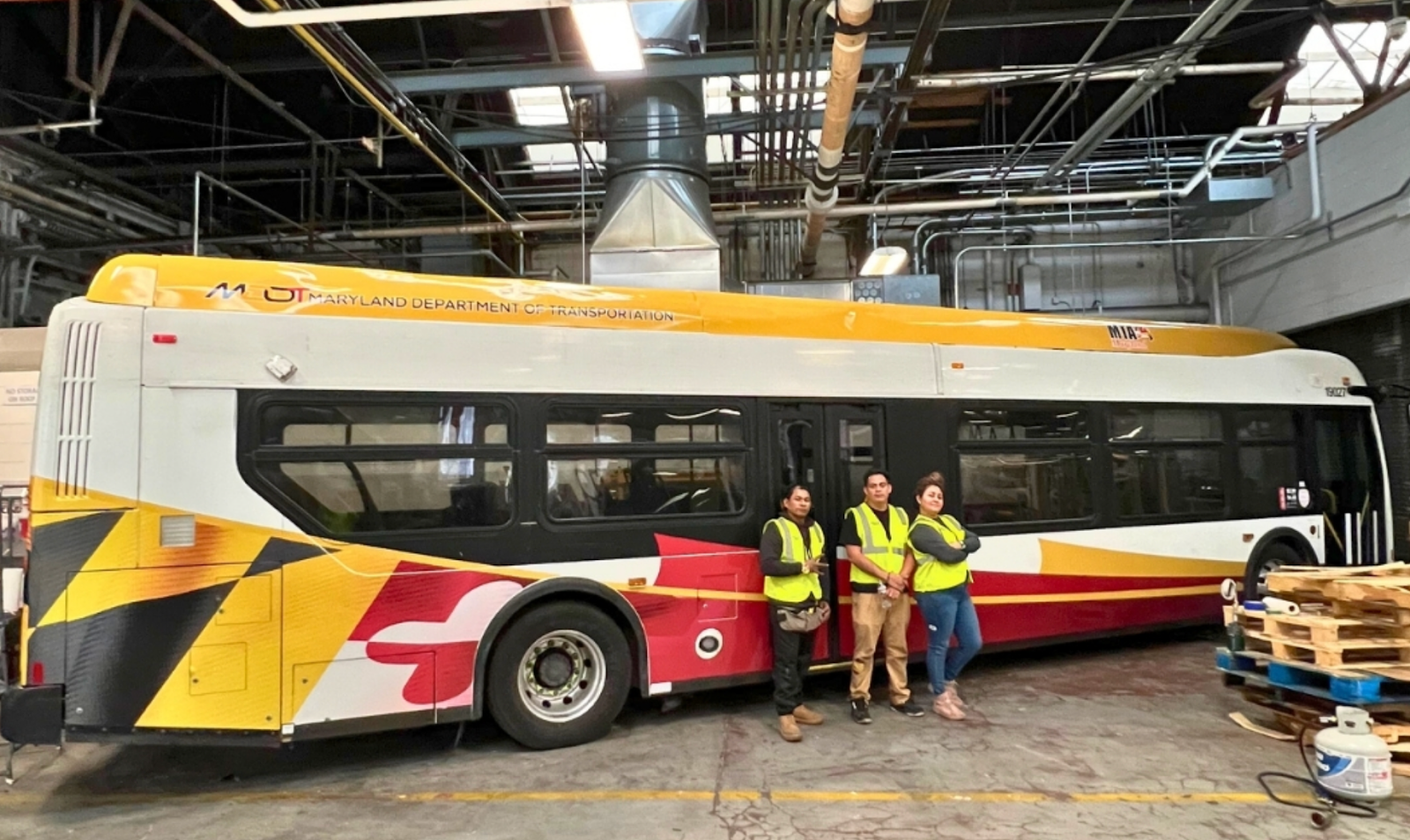 Three professionals after performing vehicle wrap maintenance on the bus.