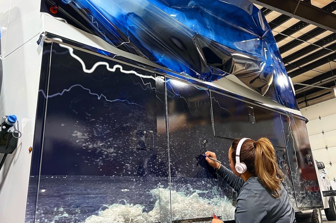 A professional installer working on a full truck wrap in a clean, well-lit garage.