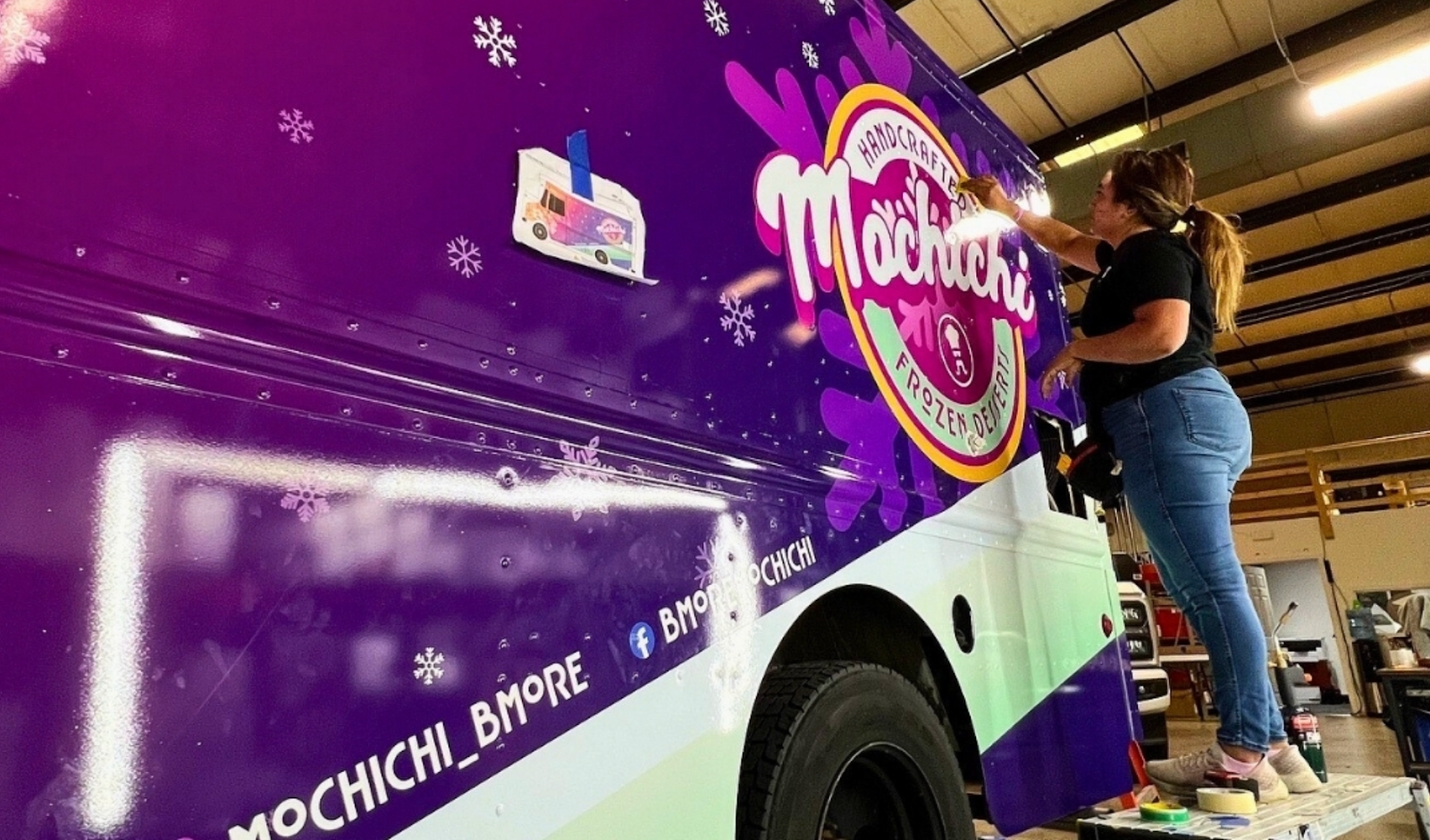 A skilled technician applying a vinyl wrap to a commercial fleet vehicle.